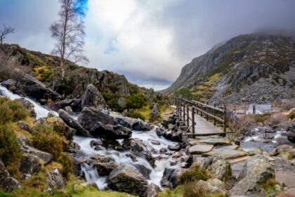 Swallow Falls in Snowdonia Wales, a rushing waterfall with a brudge and track leading into a rugged mountain Landscape
