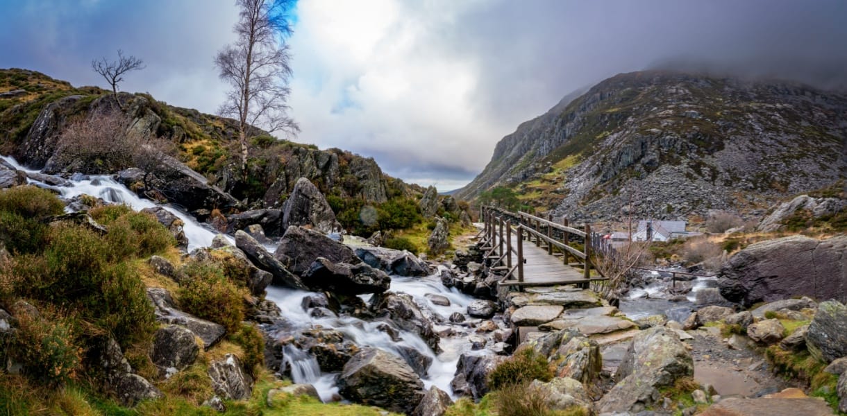 Swallow Falls in Snowdonia Wales, a rushing waterfall with a brudge and track leading into a rugged mountain Landscape