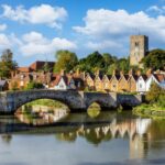 Panoramic view of Aylesford village in Kent, England with medieval bridge over the river Medway and church behind with ablue sky and fluffy white clouds