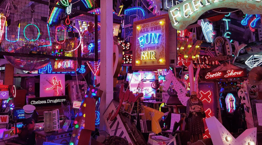 A colourful jumble of neon signs at God’s Own Junkyard in Walthamstow, London, featuring glowing slogans, vintage advertisements, and salvaged lights packed into a vibrant indoor display.