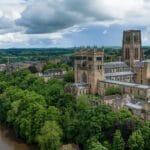 Aerial view of Durham Cathedral and River Wear surrounded by trees and historic buildings in Durham, England