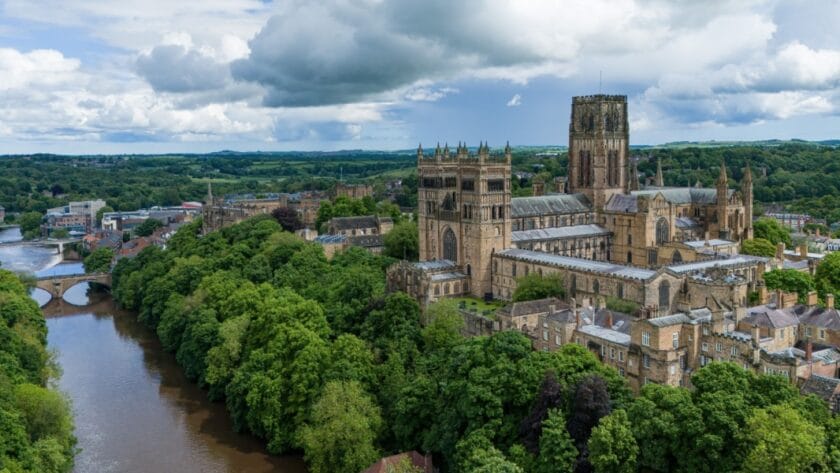 Aerial view of Durham Cathedral and River Wear surrounded by trees and historic buildings in Durham, England