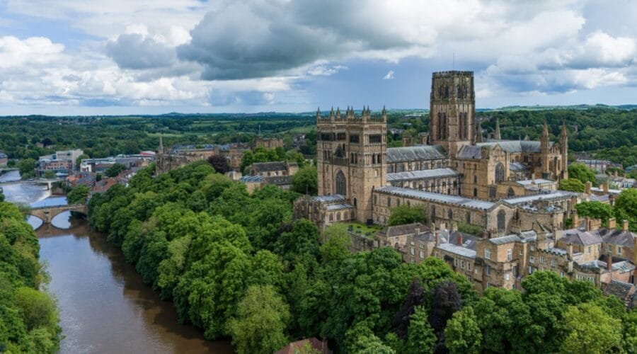 Aerial view of Durham Cathedral and River Wear surrounded by trees and historic buildings in Durham, England