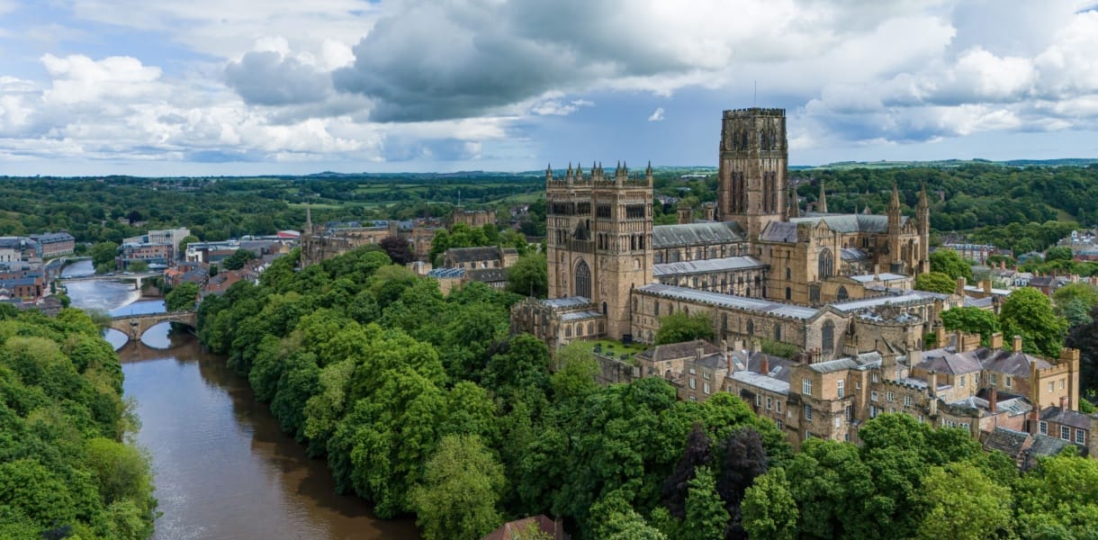 Aerial view of Durham Cathedral and River Wear surrounded by trees and historic buildings in Durham, England