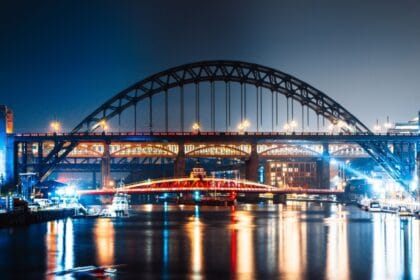 Night view of Newcastle Quayside with the illuminated Tyne Bridge, Swing Bridge, and High Level Bridge reflecting on the River Tyne