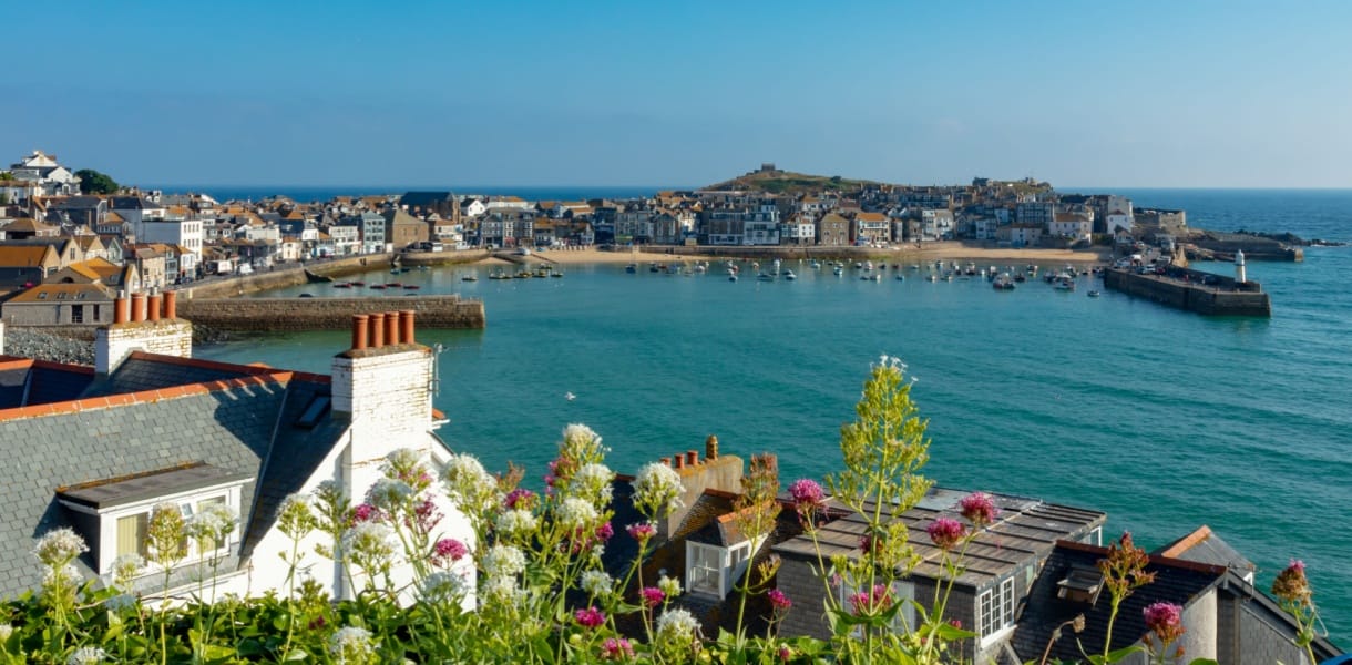 St Ives harbour in Cornwall with turquoise water, fishing boats, rooftops and sea views on a bright sunny day